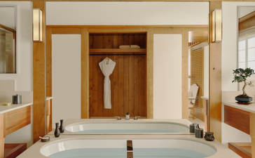 Chambre avec salle de bains spacieuse dotée d'une baignoire en marbre blanc et boiseries en chêne, Aman Le Mélézin.