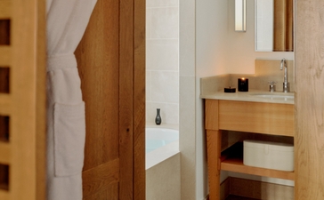 Wooden bedroom door and open shelving at Aman Le Mélézin, a village accommodation in France.