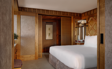 Chambre village bedroom at Aman Le Mélézin with wooden cabinetry and white bed.