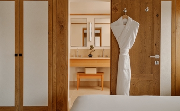 Small bedroom at Aman Le Mélézin with wooden wardrobes, white mannequin, and minimalist furnishings.
