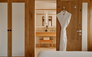 Petite chambre aux tons neutres avec armoires en bois clair et mannequin de couture blanc, Aman Le Mélézin.
