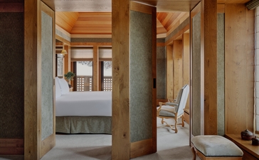 Principal bedroom suite at Aman Le Mélézin with ensuite bathroom featuring wooden partitions and warm lighting.