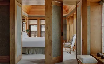 Suite bathroom at Aman Le Mélézin resort, featuring stone walls, wooden accents and contemporary fixtures.