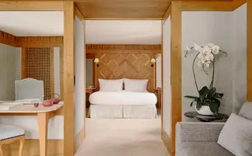 Chambre suite avec lit à baldaquin en bois, accès direct aux pistes à Aman Le Mélézin.