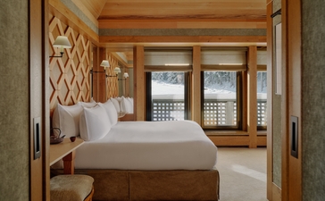 Vanoise Suite bedroom at Aman Le Mélézin with wooden bed frame and alpine views through large windows.