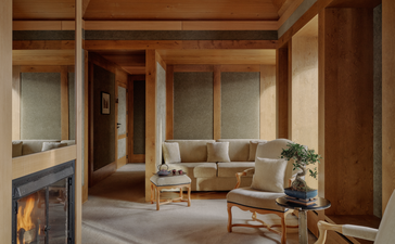 Accommodation suite at Aman Le Mélézin featuring warm wooden interiors, fireplace, and contemporary furnishings.