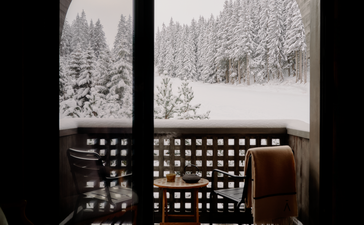 Snowy alpine landscape viewed through suite windows at Aman Le Mélézin, with latticed railings in foreground.