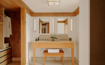 Suite bathroom at Aman Le Mélézin with wooden vanity, dual sinks and alpine views.