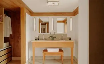 Suite bathroom at Aman Le Mélézin resort, with wooden vanity and mirror.