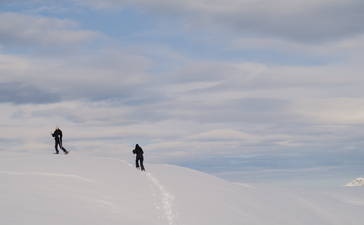 Two snowshoers traversing snowy alpine terrain at Aman Le Mélézin, France.