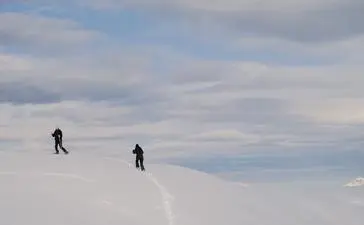 Two snowshoers traversing snowy alpine terrain at Aman Le Mélézin, France.