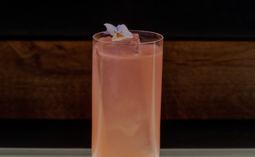 FAMP B cocktail at Aman Le Mélézin, a blush-coloured drink garnished with ice in a tall glass.