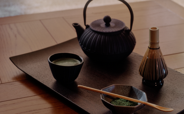 Japanese tea ceremony setup at Aman Le Mélézin with black teapot, cup, and traditional implements on wooden tray.