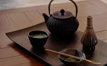 Japanese tea ceremony setup at Aman Le Mélézin with black teapot, cup, and traditional implements on wooden tray.
