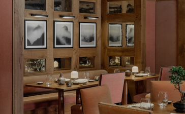 Dining room at Aman Le Mélézin with wooden cabinetry, framed artwork, and table seating.