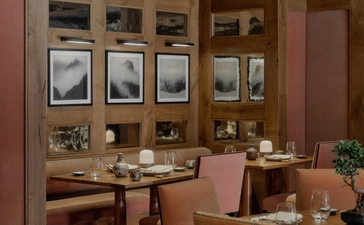 Dining room at Aman Le Mélézin with wooden cabinetry, set table, and warm terracotta walls.