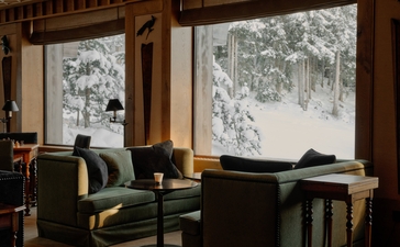 Two chairs by windows overlooking snowy landscape at Aman Le Mélézin, France.