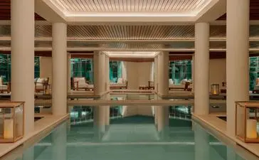 Spa and wellness pool at Aman Le Mélézin, France, with columned architecture and turquoise water.