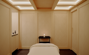Spa treatment room at Aman Le Mélézin with cream panelled walls, skylight and massage bed.
