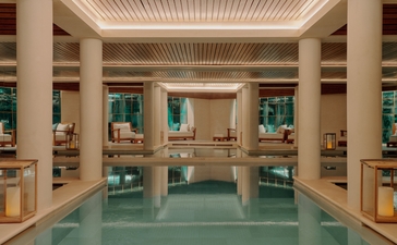 Spa wellness pool at Aman Le Mélézin with columns, soft lighting and serene turquoise water.