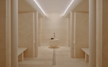 Steam room at Aman Le Mélézin with symmetrical wooden panelling and soft overhead lighting.