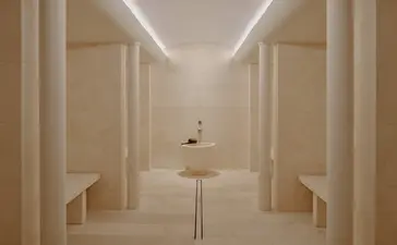 Steam room at Aman Le Mélézin with symmetrical wooden panelling and soft overhead lighting.