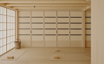 Spacious wellness room at Aman Le Mélézin resort with pale wood panelling and shoji-style window.