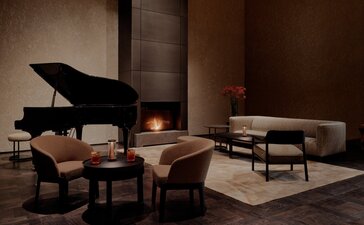 Il Salotto con pianoforte a coda e sedute in pelle presso Aman Rosa Alpina.