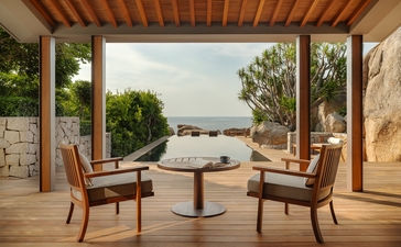安缦诺怡度假村海景住宅卧室外露台,配有两张扶手椅和圆形茶几,俯瞰宁静水景。