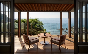 安缦诺怡度假村海景房卧室，宽敞露台配木制躺椅，俯瞰越南海岸线。