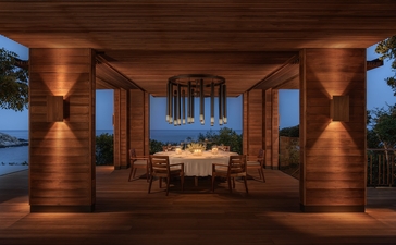 安缦诺怡度假村海景泳池住宅外部餐饮区夜景，木质柱子环绕，灯光温暖。