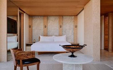 Bedroom with white bed and wooden furniture at Amanzoe resort, Greece.