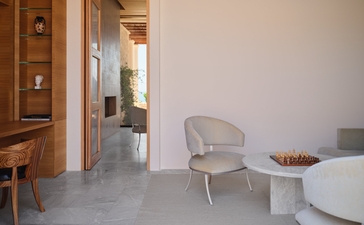 Interno di villa a tre camere ad Amanzoe, con poltrona moderna e dettagli in legno.