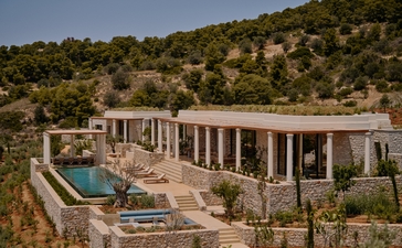 アマンゾイのリゾートにある3ベッドルームヴィラの外観。白い壁の建物とプールが緑の丘に位置しています。