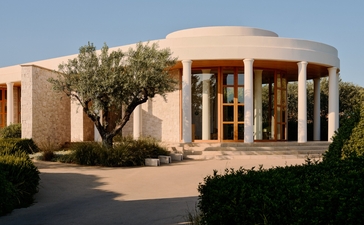 安缦卓熠度假村的圆形建筑，米色外墙配金色门窗，前庭绿化景观。