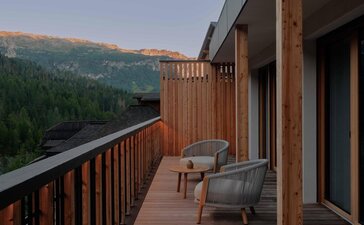 Suite terrace at Aman Rosa Alpina with alpine mountain views and seating area at dusk.