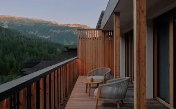 Suite terrace at Aman Rosa Alpina with alpine mountain views and seating area at dusk.
