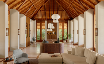 Salon spacieux de la villa Amanyara aux Îles Turques-et-Caïques, avec plafond cathédrale en bois, colonnes blanches et mobilier minimaliste.