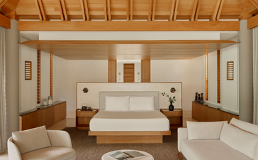 Principal bedroom at Amanyara resort, Turks and Caicos, featuring a wooden bed frame and warm neutral tones.