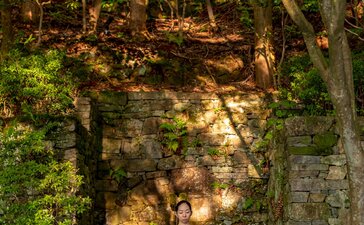 Person practising morning yoga on stone pathway surrounded by moss-covered walls and forest at Aman Kyoto.
