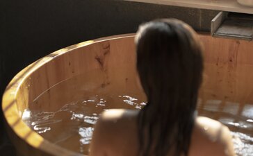 Spa treatment detail at Amandayan: guest relaxing in wooden soaking tub filled with water.