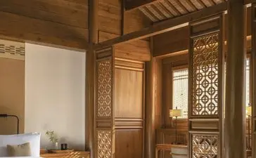 Courtyard suite at Amandayan with carved wooden pavilion, geometric lattice doors, and traditional Chinese architecture.