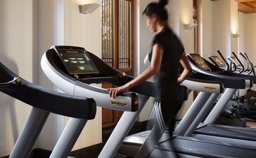 Woman running on treadmill in Amandayan's fitness centre with exposed wooden beams.