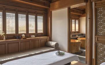 Spa treatment room at Amandayan with wooden screens, massage bed, and stone accents.