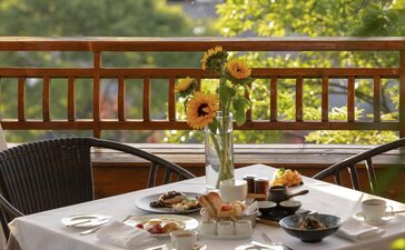 Breakfast table at Amandayan's China Pavilion with fresh flowers and morning light filtering through trees.