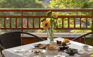 Breakfast table at Amandayan's China Pavilion with fresh flowers and morning light filtering through trees.