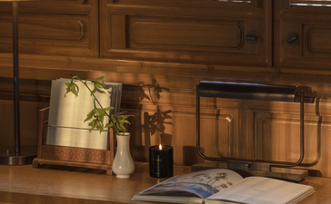 Wooden desk with desk lamp, decorative objects and open book in a courtyard suite at Amandayan, China.