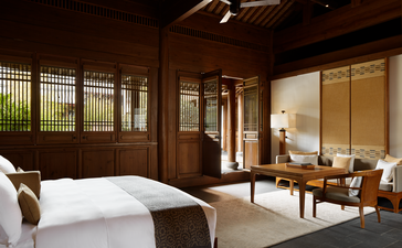 大研安缦度假村的庭院套房卧室，设有传统木质屏风、柔和照明和简约家具。