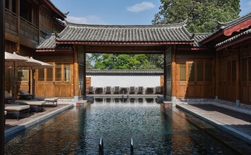 Outdoor swimming pool at Amandayan, framed by traditional Chinese architecture with wooden pavilions.