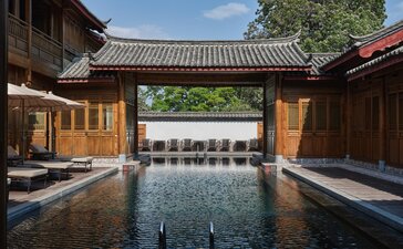 Outdoor swimming pool at Amandayan framed by traditional wooden architecture in China.